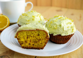 Light lemon cupcakes muffins on wooden background and a cup of tea.