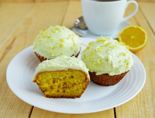 Light lemon cupcakes muffins on wooden background and a cup of tea.