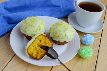 Light lemon cupcakes muffins on wooden background and a cup of tea.