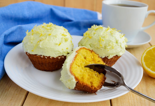 Light lemon cupcakes muffins on wooden background and a cup of tea.