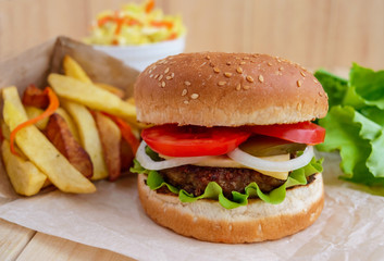 Sandwich home hamburger soft buns, cheese, tomatoes and juicy burgers. Cabbage salad. French fries. Fast food.