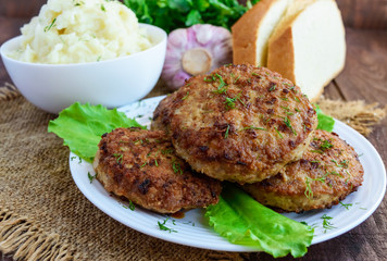 Juicy homecutlets (beef, pork, chicken) and mashed potatoes on a wooden background.