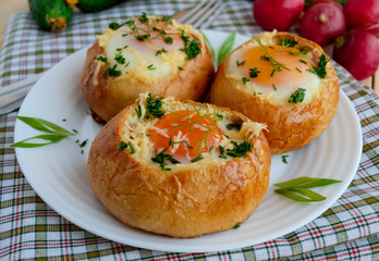 Eggs baked in a bun with ham, cheese and herbs. French breakfast.