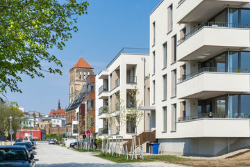 Fototapeta na wymiar Moderne Stadtwohnungen und alte Kirche im Hintergrund