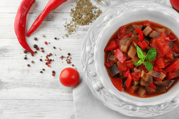 Ratatouille in bowl, on wooden table background