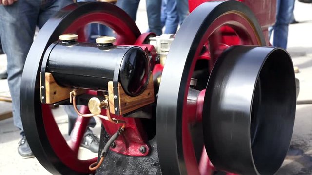 People watch engineer starting retro steam engine, closeup of old machinery

