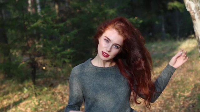 Pretty girl poses with her red hair in sunny forest