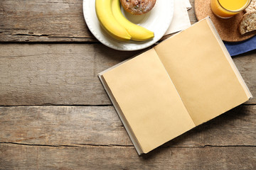 Open book and snack on wooden table background