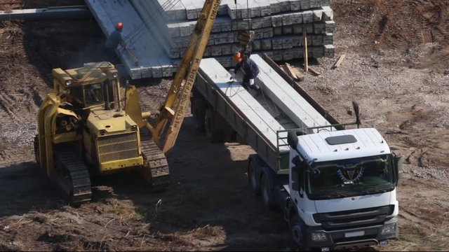 PERM, RUSSIA - SEP 28, 2015: Tractor with crane hook unloads concrete piles on construction site of largest developer Perm factory of silicate panels