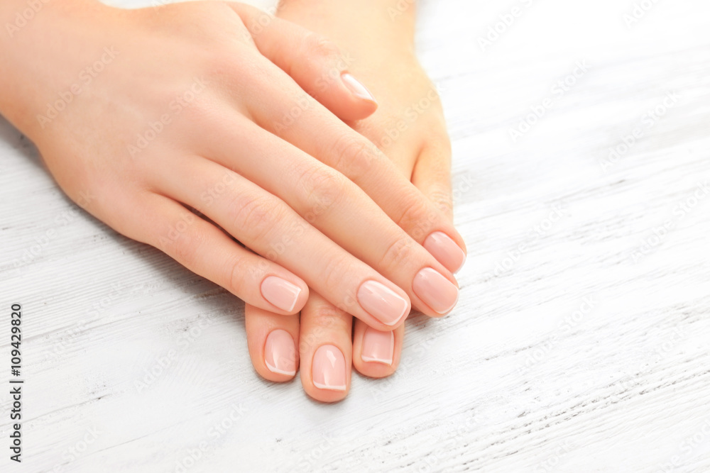 Wall mural woman hands with beautiful manicure on wooden background