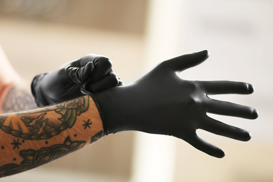 Naklejka Man with tattoo wearing black latex gloves on blurred background