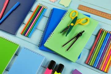School set with notebooks, scissors and colored pencils on wooden blue background