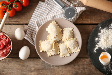 Uncooked ravioli on plate on wooden table