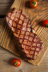 Grilled steak on cutting board with cherry tomatoes, closeup