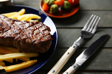 Grilled steak with french fries and vegetables, closeup