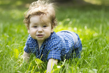 Beautiful child sitting in the green grass. Child outdoors. Children walk. Walk with the child. summer vacation
