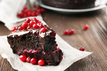 Piece of chocolate cake with cranberries on parchment, closeup