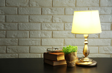 Night lamp and books on the desk on white brick wall background