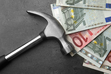 Money with hammer on grey background, close up