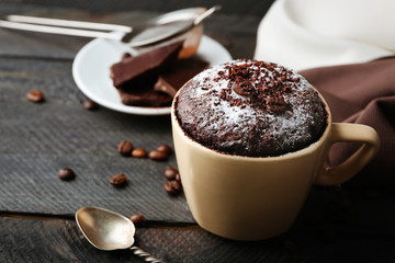 Chocolate fondant cake in cup on wooden background
