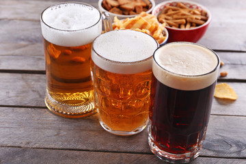 Various types of beer and snacks on wooden table