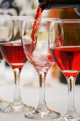 Red wine pouring into glasses, closeup