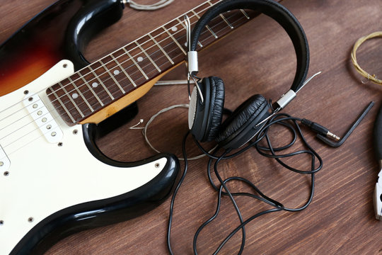 Guitar with headphones on wooden surface closeup