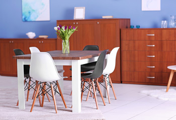 Modern living room. Furniture set with table and chairs. Bouquet of beautiful white and purple tulips on the table