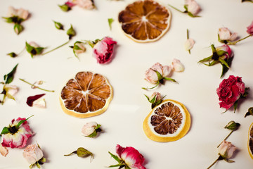 Fototapeta na wymiar Beautiful background with roses and dried flowers dried round slices of lemon laid on a white background
