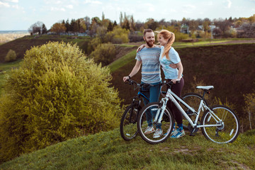 Obraz premium Beautiful young couple in love walking with bicycles hugging and looking at each other. The concept of joy and happiness