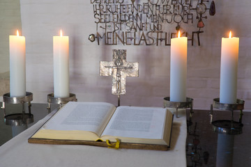 Altarraum mit Bibel, Kreuz und brennenden Kerzen, sakral, andächtig,  Szene, warmes Licht...
