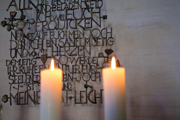 warmes, heimeliges Kerzenlicht im Altarraum, zwei brennende Kerzen mit ruhiger Flamme