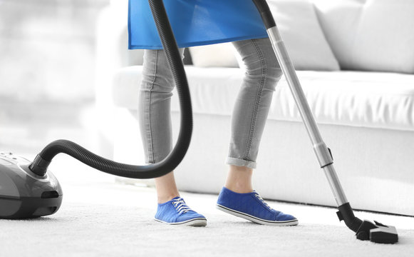 Cleaning concept. Young woman cleaning carpet with vacuum cleaner, close up