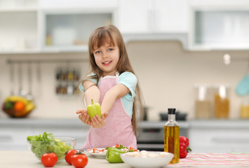 Little girl holding a green pepper.