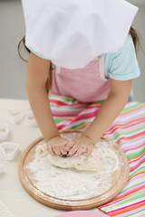 Beautiful little girl rolling the dough.