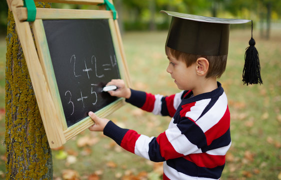 little happy boy writing on blackboard