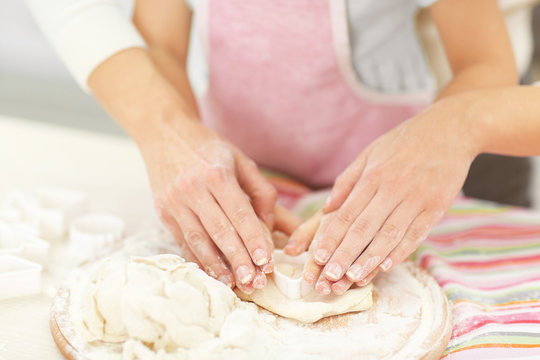 Mother and daughter kneading a dough.
