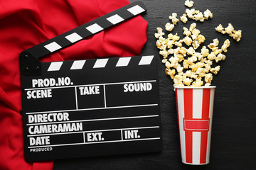 Movie clapper board with popcorn on the wooden table.