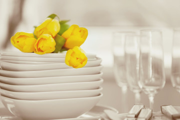 Set of dishes with yellow tulips for dinner party, close up