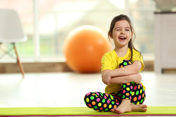 Fototapeta na wymiar Little funny girl sitting on a mat indoor