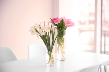 Fototapeta na wymiar Beautiful tulips and irises on dinning table against white wall background