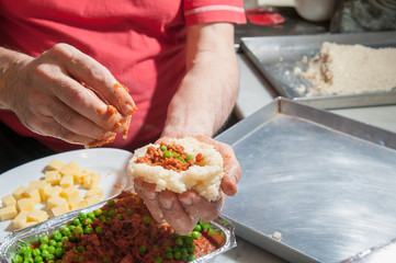 The making of sicilian arancini: cook modelling a rice arancino filled with italian ragu in a typical cone shape