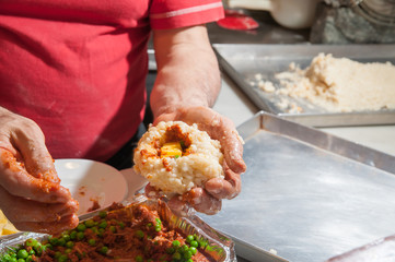 The making of sicilian arancini: cook modelling a rice arancino filled with italian ragu in a typical cone shape