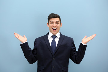 Attractive young man in a suit against light blue wall
