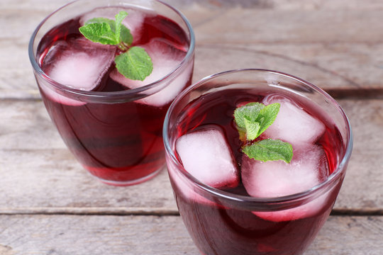 Glasses of cherry soda with ice and fresh mint on rustic wooden background