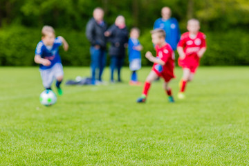 Blurred kids playing youth football match - obrazy, fototapety, plakaty