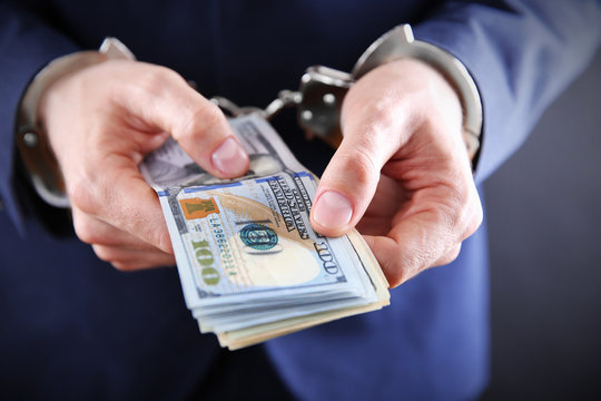 Man in handcuffs counting dollar banknotes, close up