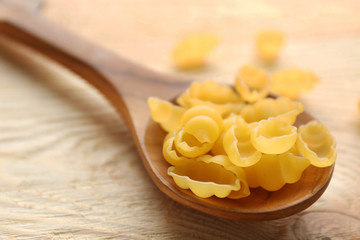 Dry gnocchi pasta in wooden spoon on a table