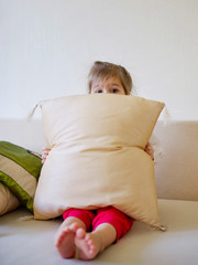 cute girl hiding behind pillow