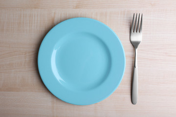 Empty plate with silver fork and knife on wooden background